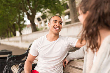Male and female city runners chatting on benchの写真素材