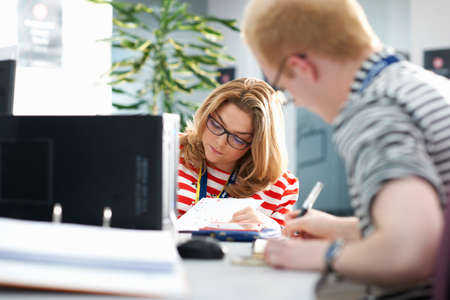 Teacher and female student writing in classroom tutorialの写真素材
