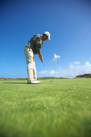 Low angle full length side view of golfer puttingの写真素材
