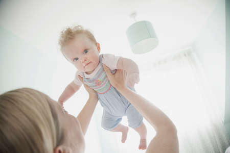 Mother holding baby daughter in air