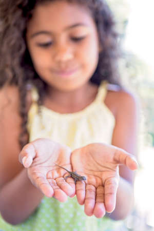 Girl holding small reptile on palm of hands, focus on foregroundの写真素材