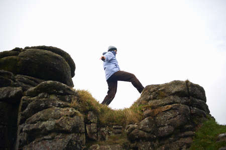 Low angle view of woman on rock formation, Dartmoor, Devon, UKの写真素材