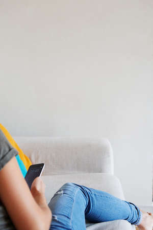 Woman using smartphone on sofa