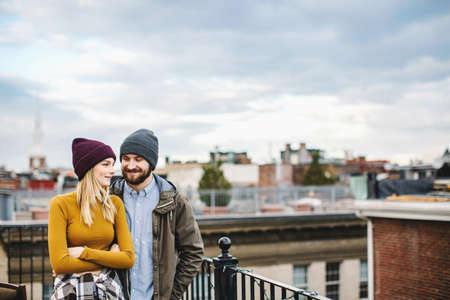 Young couple standing on city rooftop terraceの写真素材