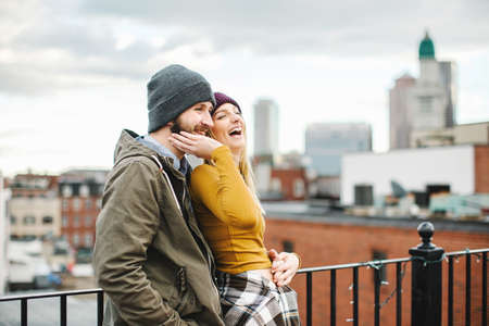 Young couple laughing on city rooftop terraceの写真素材