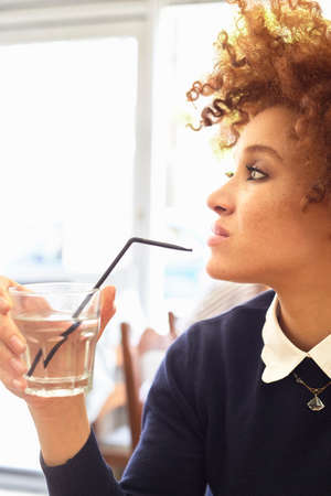 Young stylish woman drinking water in cafe