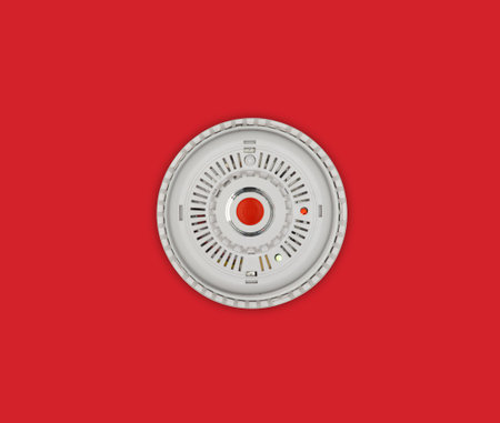 Smoke alarm with red button on red backgroundの写真素材