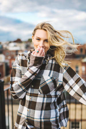 Portrait of young woman with flyaway hair on rooftop terraceの写真素材