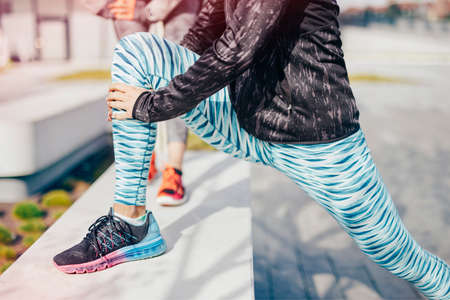 Neck down view of female runners warming up on city wallの写真素材