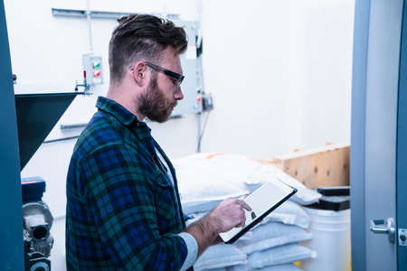 Side view of young man in storage room using digital tablet