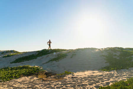 Young man running along sand dunesの写真素材