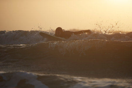 Silhouette of young male surfer surfing in sea, Devon, England, UK