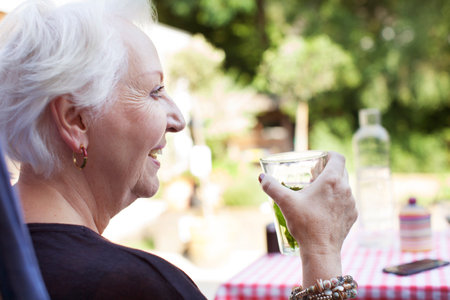 Senior woman relaxing in garden, holding cold drinkの写真素材