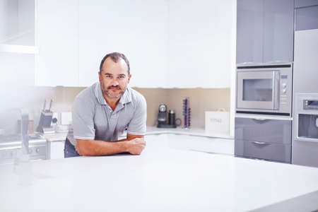 Portrait of mature man leaning on kitchen counterの写真素材
