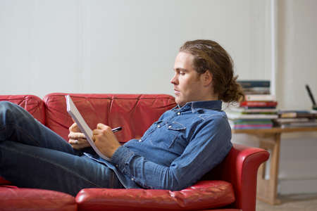 Man writing notes on couch