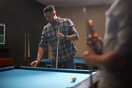 Man preparing to play pool, friend with beer in foreground