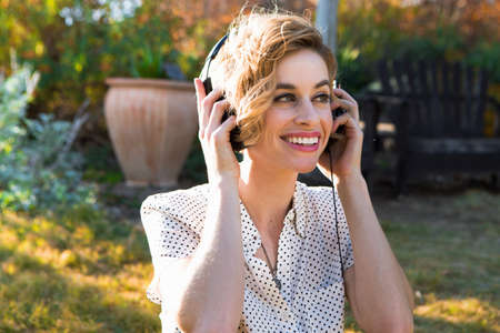 Mid adult woman wearing headphones, outdoors, smilingの写真素材