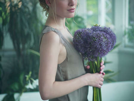 Young woman holding bouquet of flowers, mid sectionの写真素材