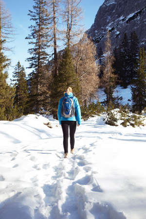 Rear view of young woman hiking through mountain snow, Austria