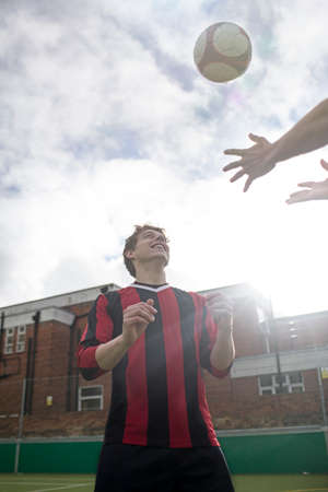 Two young men playing with football on urban football pitch