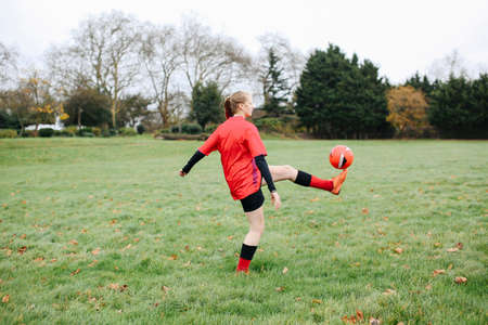 Teenage female soccer player practicing keepy uppy in parkの写真素材