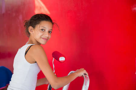 Portrait of girl on step ladder painting red wallの写真素材