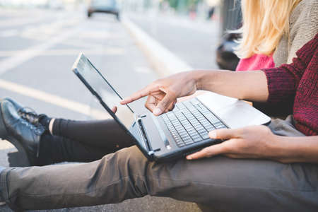 Couple using laptop on pavement