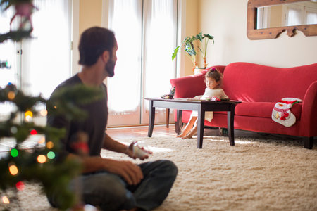 Girl sitting on sofa, father in foregroundの写真素材