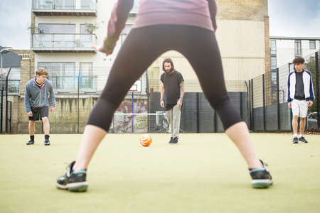 Group of adults playing football on urban football pitch