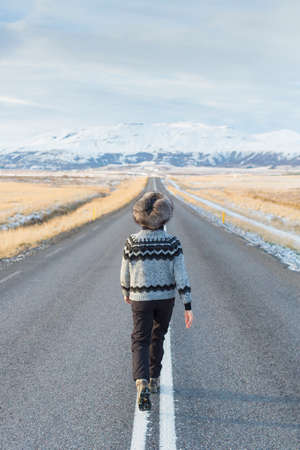 Woman walking in middle of country road, Icelandの写真素材
