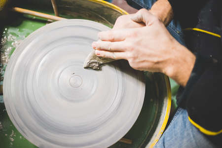 Overhead view of mid adult mans hands cleaning pottery wheelの写真素材