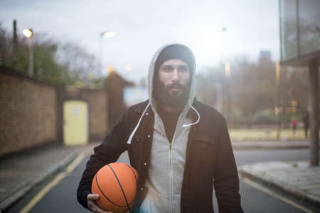 Portrait of mid adult man in street, holding basketballの写真素材