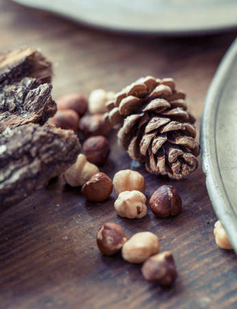 Cropped close up view of hazelnuts and pinecones on wooden surfaceの写真素材