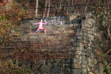Young woman doing stretching exercises on overgrown stone steps
