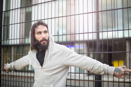 Mid adult man standing against fence, looking away