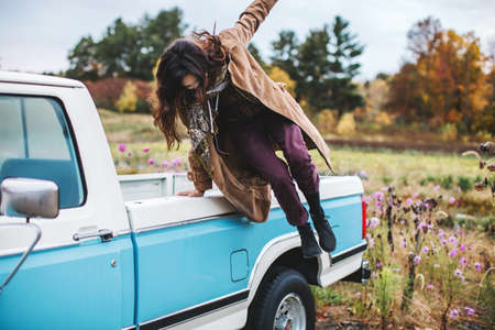 Young woman jumping from back of truckの写真素材