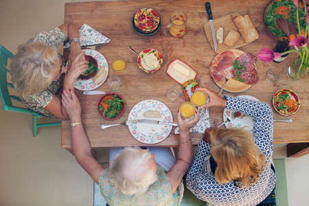 Three women having lunch together at home, overhead viewの写真素材