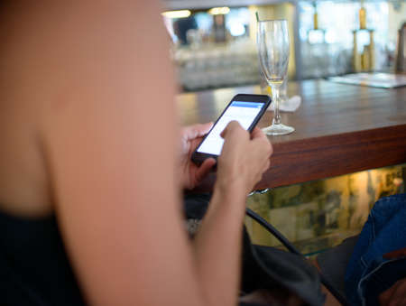 Cropped shot of woman using smartphone touchscreen at barの写真素材