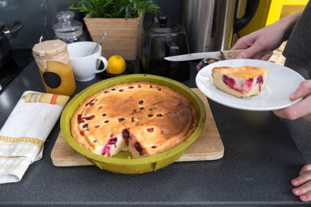 Female hands holding plate with baked cake at kitchen counter