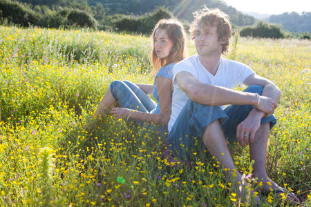 Romantic young couple sitting back to back in wildflower field, Majorca, Spainの写真素材
