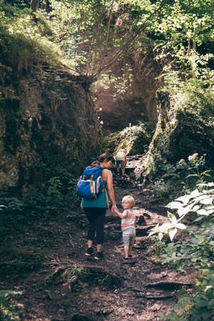 Full length rear view of mother and sons hiking up trail, looking over shoulder at camera smiling, Bludenz, Vorarlberg, Austriaの写真素材