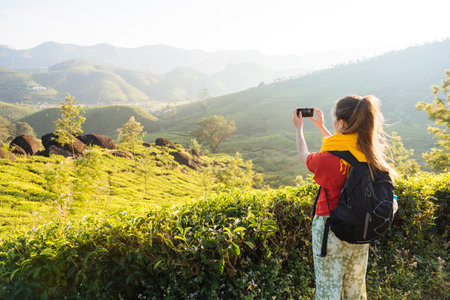 Young woman photographing tea plantations near Munnar, Kerala, Indiaの写真素材