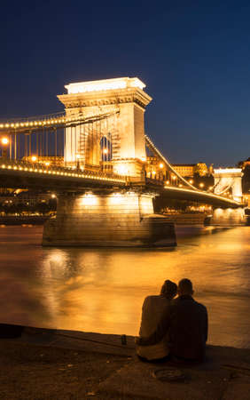 Couple on the Danube bank, Chain Bridge in background, at night, Hungary, Budapestの写真素材