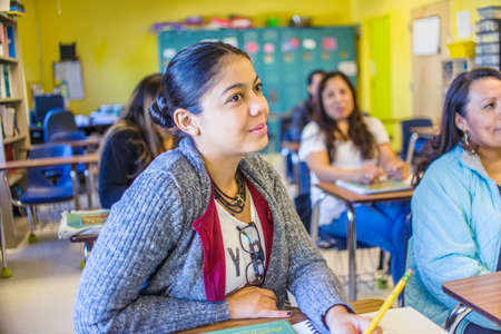 Female and male mature students listening from class desksの写真素材