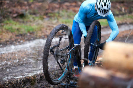 Cyclist wearing bicycle helmet repairs upside down bicycle