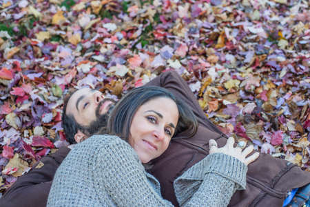 Couple lying on autumn leaves in gardenの写真素材