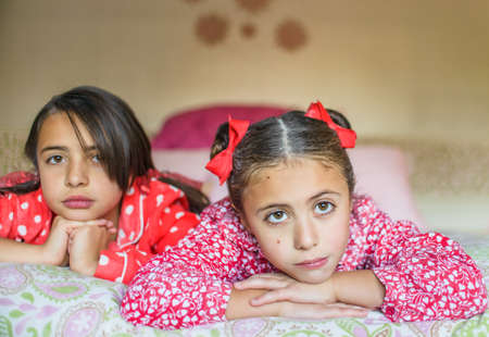 Portrait of two sisters lying on bed gazingの写真素材