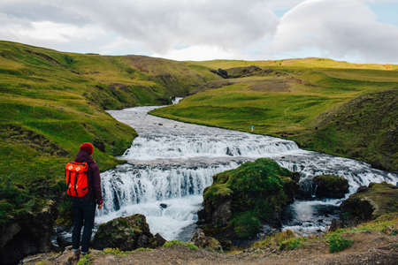 Rear view of mid adult man looking at river flowing through lush green landscape, Icelandの写真素材