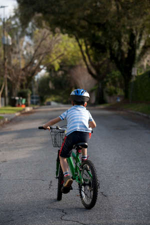 Boy riding bicycle in middle of roadの写真素材