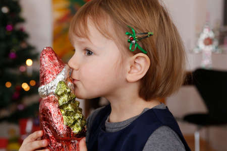 Side view of girl kissing christmas ornament of santaの写真素材